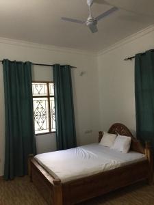 a bedroom with a bed with green curtains and a window at Gabibo Kendwa Beach House in Kendwa