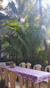 uma mesa roxa com cadeiras brancas e palmeiras em आंगण होम स्टे em Malvan
