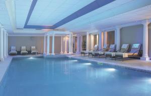 una piscina en un hotel con sillas y una piscina en Macdonald Linden Hall Hotel, Golf & Spa, en Longhorsley