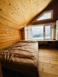 KrivopolʼyeにあるKam Inの窓のある木造の部屋のベッド1台分です。