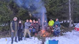 un grupo de personas de pie alrededor de un fuego en la nieve en Agroturystyka na Słonecznej Orawie u Dzikich en Jabłonka
