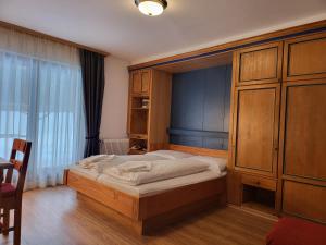 1 dormitorio con 1 cama y armario de madera en Gasthof Ramona, en Scharnitz