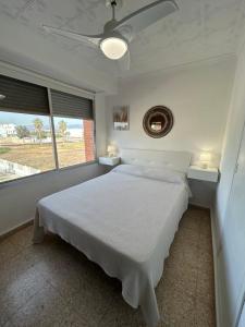 een witte slaapkamer met een bed en 2 ramen bij Almenara Beach in Almenara
