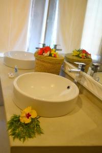 - une salle de bains avec 2 lavabos et des fleurs sur un comptoir dans l'établissement Aquarius Club, à Watamu
