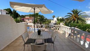 een tafel en stoelen op een balkon met een parasol bij B&B Casa Sardonyx in Calpe