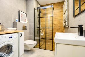 een badkamer met een wasmachine en een wastafel bij River House - J&D Apartamenty in Szczecin