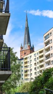 a building with a church steeple in the background at River House - J&D Apartamenty in Szczecin