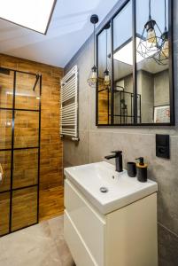 een badkamer met een witte wastafel en een spiegel bij River House - J&D Apartamenty in Szczecin