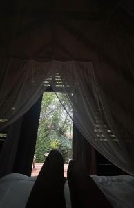 a person sitting on a bed looking out a window at Casa Embira - 300 metros da Praia do Lago Verde in Alter do Chao