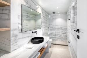 a bathroom with a sink and a shower at Panormos Bay Suites Luxury Resort in Panormos Mykonos