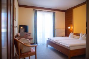 ein Schlafzimmer mit einem Bett, einem Stuhl und einem Fenster in der Unterkunft GASTHOF SCHEER Feriendomizil in Bad Gleichenberg