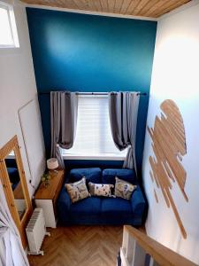 niebieską kanapę w pokoju z oknem w obiekcie The Wee Tiny Home w mieście Eglinton