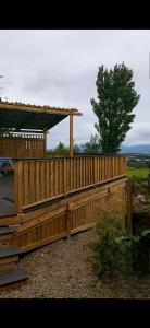 a wooden deck with a gazebo and a tree at The Wee Tiny Home in Eglinton