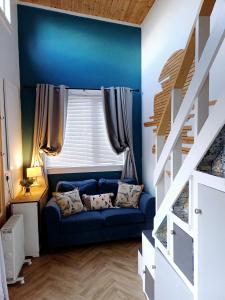 niebieski pokój z niebieską kanapą i oknem w obiekcie The Wee Tiny Home w mieście Eglinton