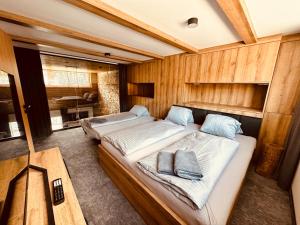 2 camas en una habitación con paredes de madera en Luxusní Apartmány Domovjanka - LYSÁ HORA A SMRK, en Bílá
