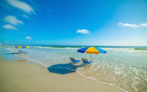 dos sillas y dos sombrillas en una playa en 3 BR Direct Oceanfront Condo Wyndham Ocean Walk Resort - Daytona Funland 1023 en Daytona Beach