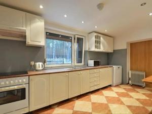 a kitchen with white cabinets and a checkered floor at Leśna Odnowa in Borków