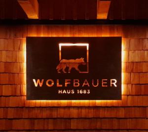 a sign for a wolf dealer on a brick wall at Haus 1683 - Wolfbauer in Johnsbach