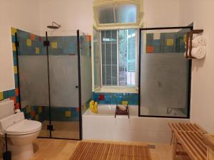 baño con bañera, aseo y ventana en fishpond garden place דירת גן ובריכת דגים - תלפיות en Haifa