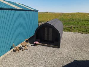 a black tent sitting next to a building at The Sandy Pod in Stornoway