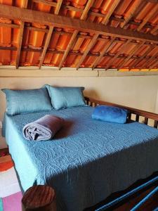 uma cama com lençóis e almofadas azuis num quarto em Caridade Loft em Monte das Gameleiras