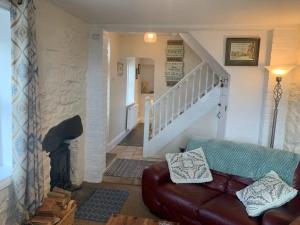 a living room with a couch and a staircase at Cosy Two Bedroom Cottage with Fireplace in Colwyn Bay