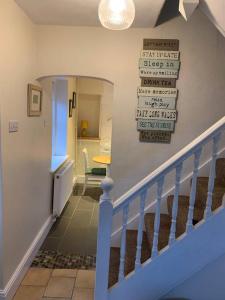 a hallway with a staircase with a sign on the wall at Cosy Two Bedroom Cottage with Fireplace in Colwyn Bay