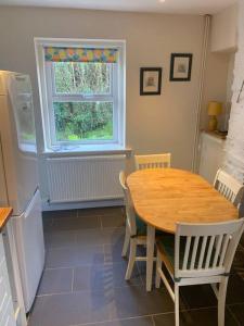 a kitchen with a wooden table and a window at Cosy Two Bedroom Cottage with Fireplace in Colwyn Bay