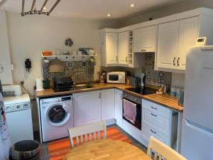 a kitchen with white cabinets and a washing machine at Cosy Two Bedroom Cottage with Fireplace in Colwyn Bay