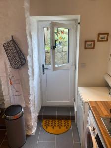 a kitchen with a white door and a window at Cosy Two Bedroom Cottage with Fireplace in Colwyn Bay