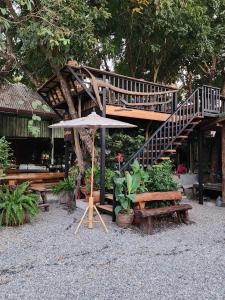 een houten trap en banken met een paraplu bij Suk Sabai Homestay in Sukhothai