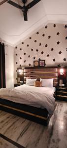 ein Schlafzimmer mit einem großen Bett mit schwarzen Sternen an der Wand in der Unterkunft Luxe Ganga view Villa with Terrace Seating (Vacaow) in Rishikesh