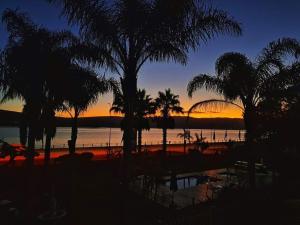 a sunset over a beach with palm trees and the ocean at Lagoon Breeze Guest House in Knysna