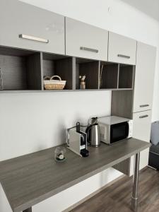 uma cozinha com armários brancos e uma mesa com um micro-ondas em Apartment Vlora-Naturblick em Villach