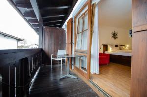 Habitación con balcón con mesa y cama. en s`Wirtshaus Hotel & Restaurant en Oberammergau