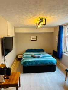 a bedroom with a bed with a blue comforter at Newly refurbished - Near seafront - Retro games machine - Central Brighton - 1 bedroom apartment in Brighton & Hove