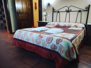 Una cama en una habitación con colcha. en Casa Rural Los Olivos en Sotoserrano