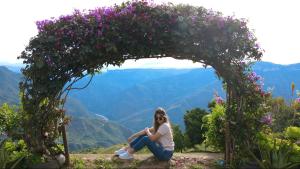 a woman sitting under an arch with flowers at Cabañas Cañon Del Chicamocha in Aratoca