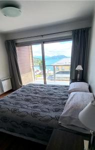 een slaapkamer met een bed en een groot raam bij Duplex Quinta Luna in Bariloche