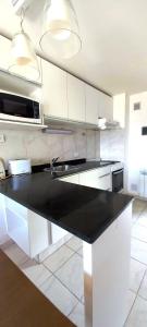 a kitchen with white cabinets and a black counter top at Duplex Quinta Luna in San Carlos de Bariloche