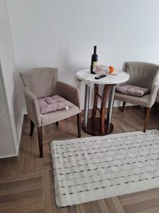 uma mesa e duas cadeiras e uma mesa com uma garrafa de vinho em Apartman Emily em Nikšić