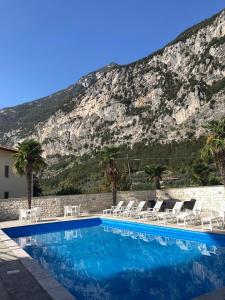 una piscina con sillas y una montaña en el fondo en Hotel Miramonti, en Dro