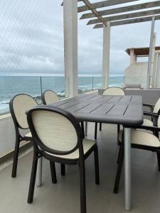 una mesa y sillas en un balcón con vistas al océano en Depto. Maitencillo 3 dormitorios, 2 estacionamientos, gran terraza frente a la playa, en Valparaíso
