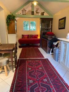 sala de estar con alfombra roja en el suelo en Maisonnette en clairière de forêt, en Gambais