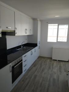 a kitchen with white cabinets and a wooden floor at Casa Blanca in Oliva