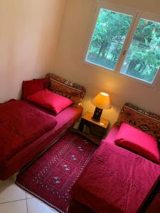 Habitación con 2 camas y mesa con lámpara. en Maisonnette en clairière de forêt, en Gambais