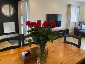 a vase of red roses sitting on a wooden table at Bungalow33 Benllech in Benllech