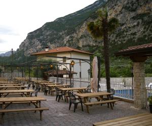 uma fila de mesas e cadeiras de madeira em frente a uma montanha em Hotel Miramonti em Dro