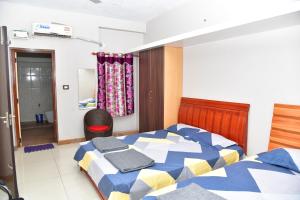 a bedroom with a bed with a blue and yellow comforter at Akash Avenue Soniya Service Apartment in Tirunelveli