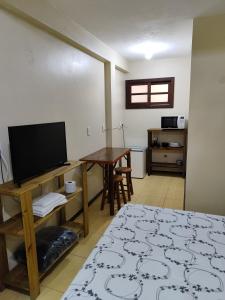 ein Wohnzimmer mit einem TV und einem Tisch in der Unterkunft Nalua Guest House in Guarda do Embaú
